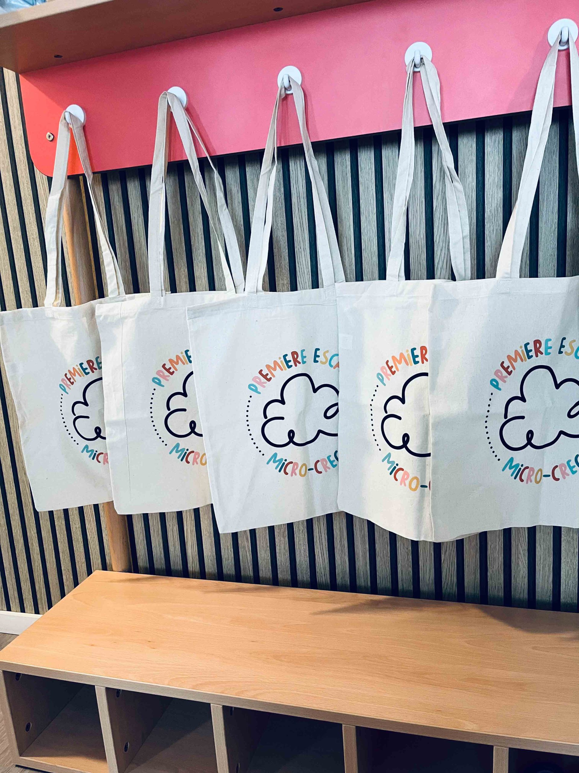 Porte manteaux avec totebag estampiller du logo première escale, la micro crèche de Colmar